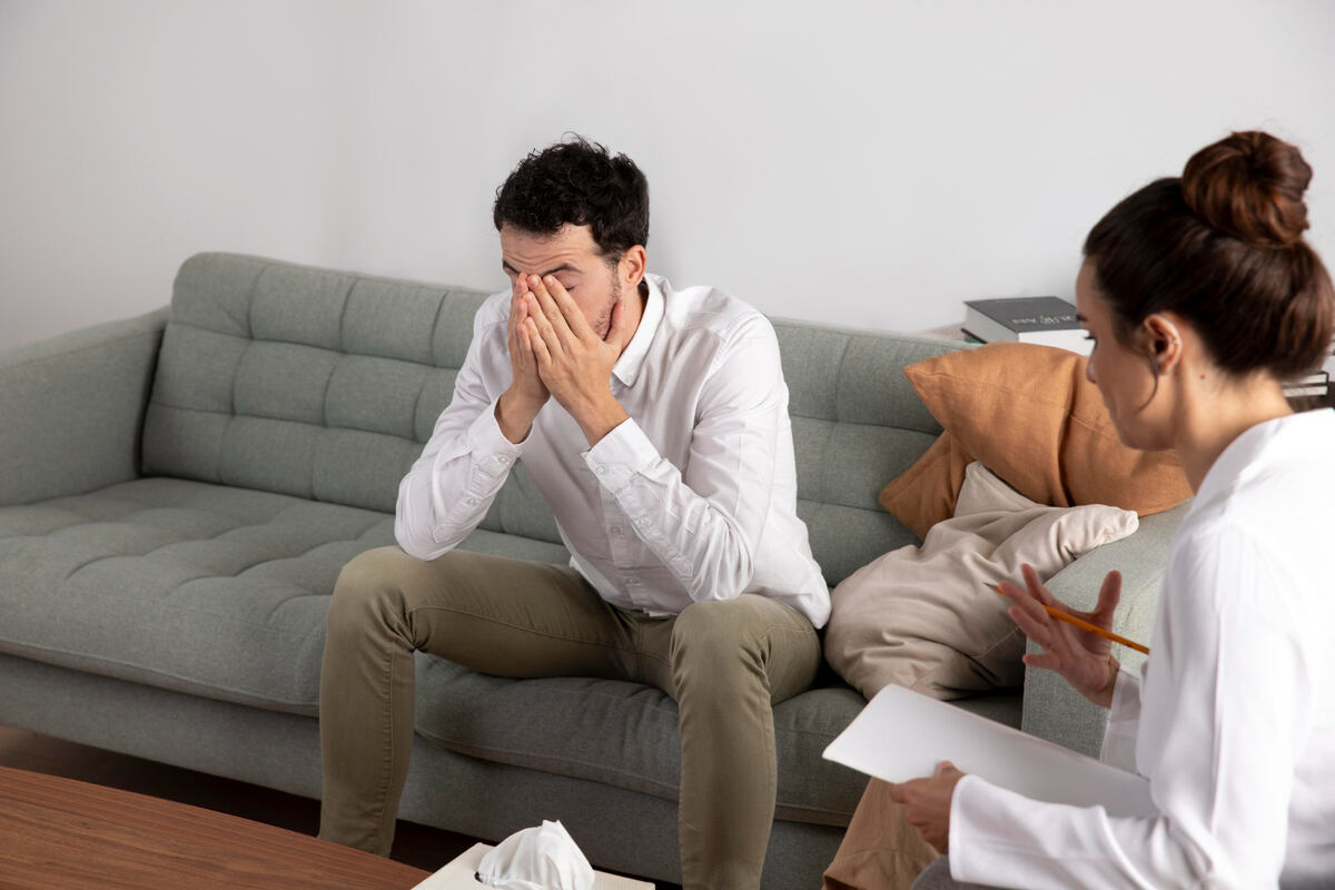 Man covering face during therapy session with counselor