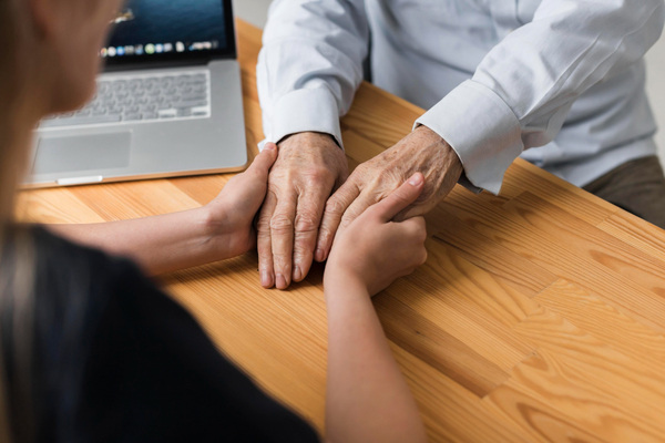Young person holding elderly hands during support