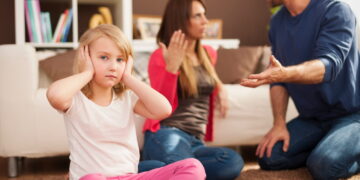 A child covering her ears because her parents are quarreling