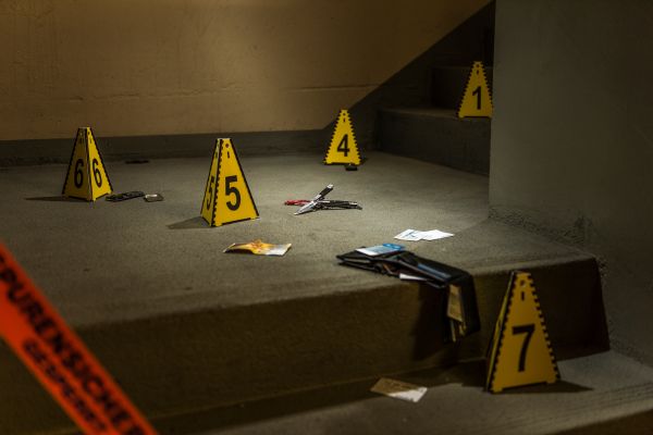 Crime scene by the stairs with evidence markers and tape.