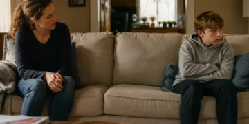 Parent and reluctant pre-teen sitting apart on a sofa before reunification therapy